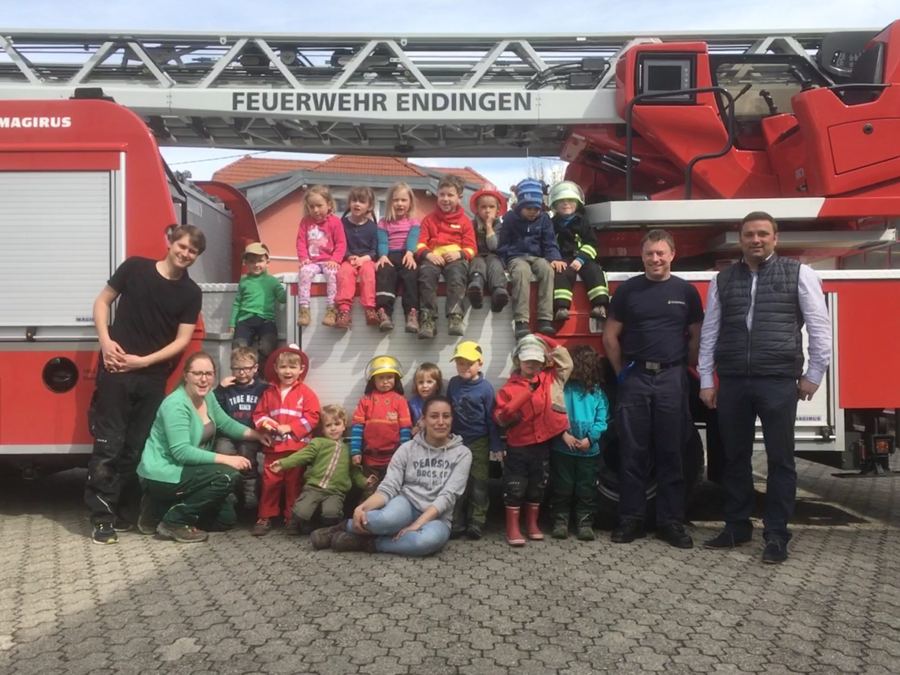 Kindergartengruppe mit Erziehern und Feuerwehrleuten vor der Drehleiter der Feuerwehr Endingen