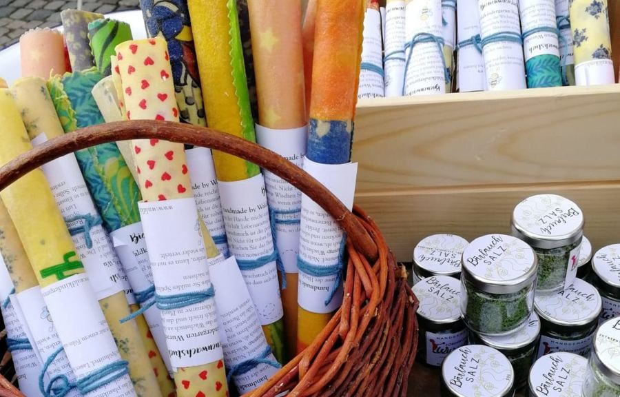Gerollte Bienenwachstücher im Weidenkorb neben Gläsern mit Bärlauchsalz
